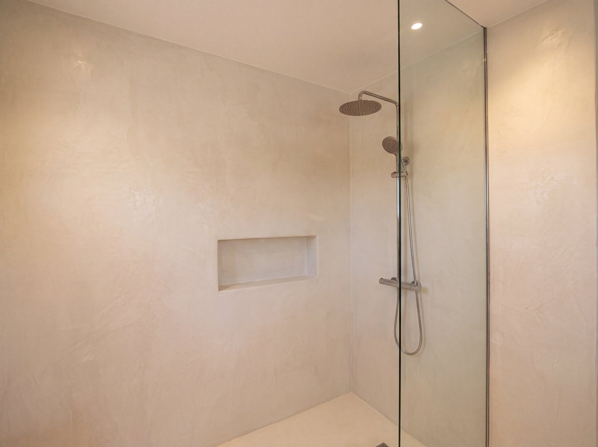 Pared y nicho de ducha en microcemento continuo, con ducha efecto lluvia