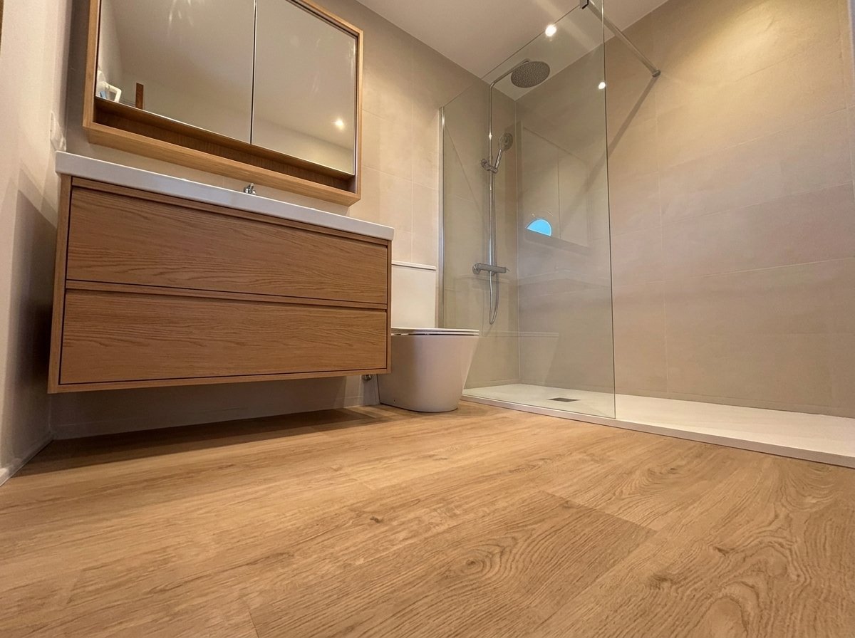 Baño con suelo de parquet instalado, mueble suspendido y mampara de ducha, acabado final